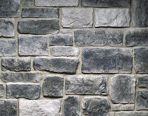 Hackett-Smokey-Grey Gray stone brick wall with rough, rectangular stones set in mortar, showing a textured surface pattern.