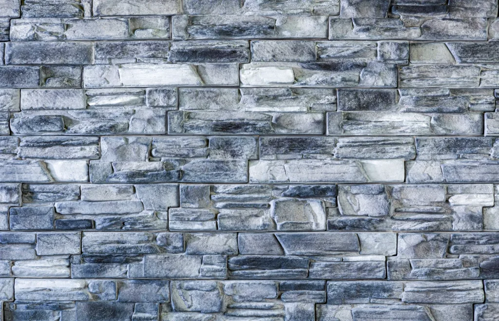 Gray stone bricks arranged in a horizontal pattern, forming a textured wall surface.