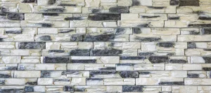 Wall made of rectangular white and gray stones arranged in a staggered pattern.