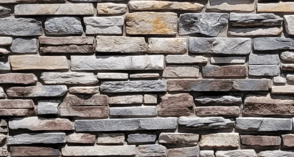 Mountain Ledge – Blue Ridge A close-up of a brick wall made of variously colored and sized rectangular stones.