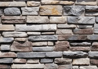 A close-up of a brick wall made of variously colored and sized rectangular stones.