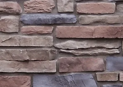 A close-up of a stone brick wall with irregular shapes in shades of brown, tan, and gray.