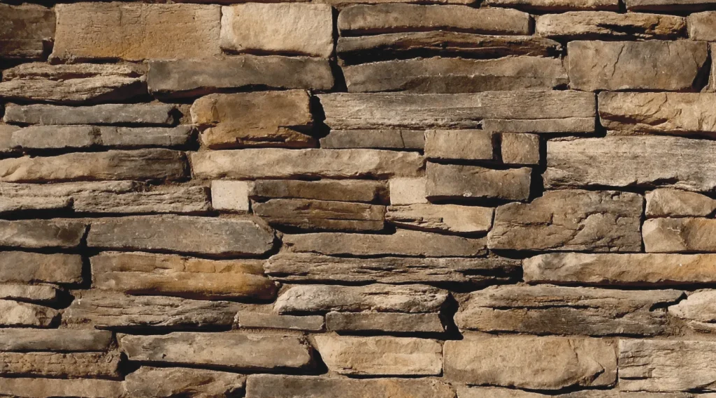 Mountain Ledge – Carmel-3 A close-up of an uneven stone wall with various sized rectangular rocks stacked together.