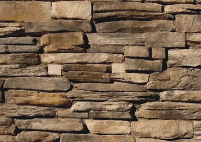 A close-up of an uneven stone wall with various sized rectangular rocks stacked together.