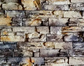 Stone wall with uneven, rectangular, grey and beige stones stacked in a brick-like pattern.