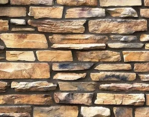 Close-up of a wall made of irregularly shaped tan and brown stones stacked horizontally.