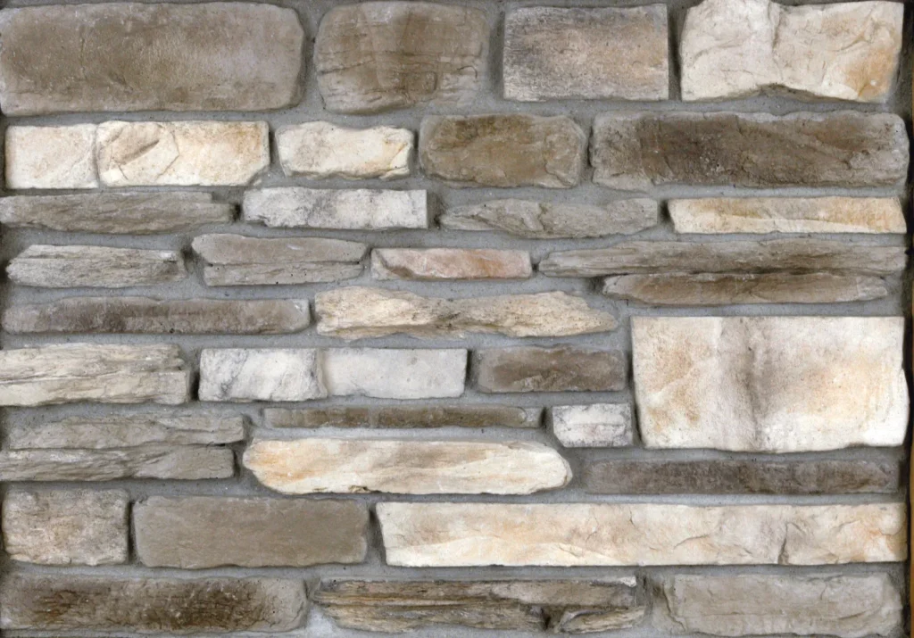 A wall made of rectangular, unevenly sized beige and gray stones with visible mortar between them.