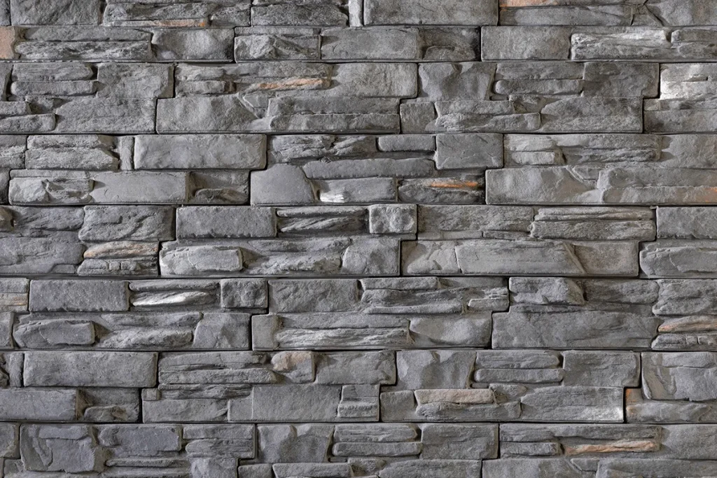 Gray stone bricks arranged in a horizontal pattern, forming a textured wall surface.