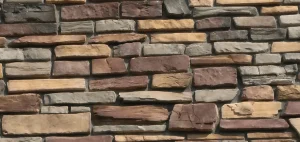 A wall made of rectangular stones in various shades of brown, tan, and gray, stacked unevenly.
