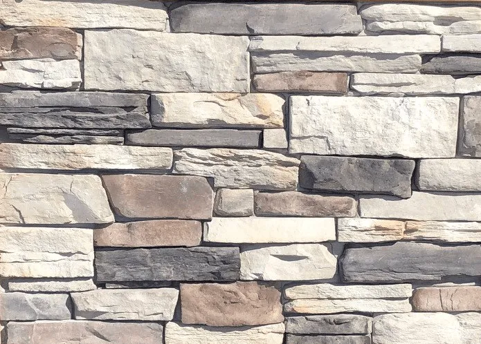 Mountain Ledge – Yukon A wall made of rectangular stones in various shades of gray, beige, and white, stacked unevenly.
