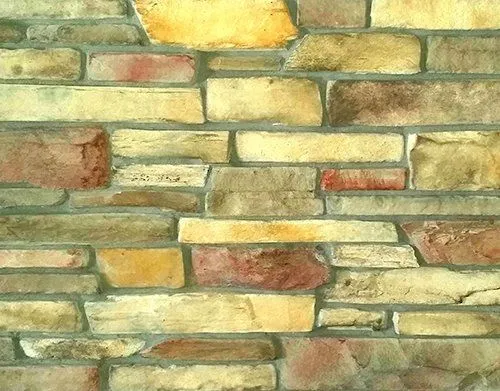 Prairie-Ledgestone-Caspian A close-up of a multicolored stone brick wall with yellow, tan, and reddish stones in a random pattern.