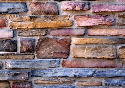 Close-up of a multicolored stone brick wall with various shades of brown, gray, and red bricks.