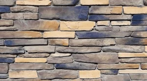 A close-up of a wall made of unevenly stacked rectangular stones in tan and gray shades.