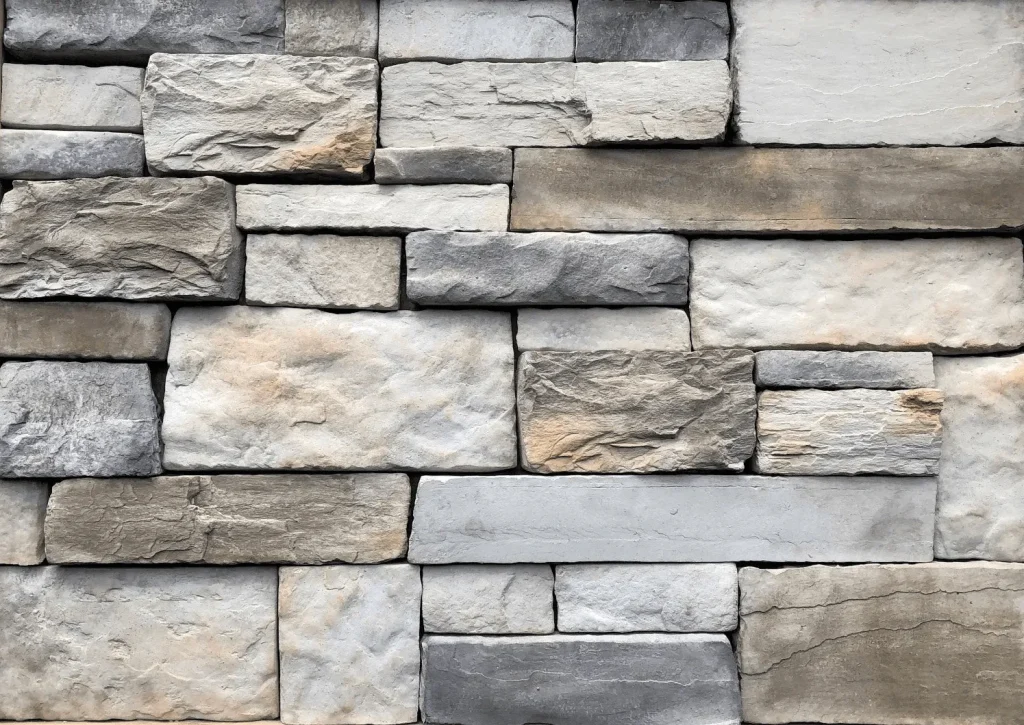 Quarry-Blend-Aspen A close-up of a stone wall with rectangular, unevenly sized gray and beige stones stacked together.