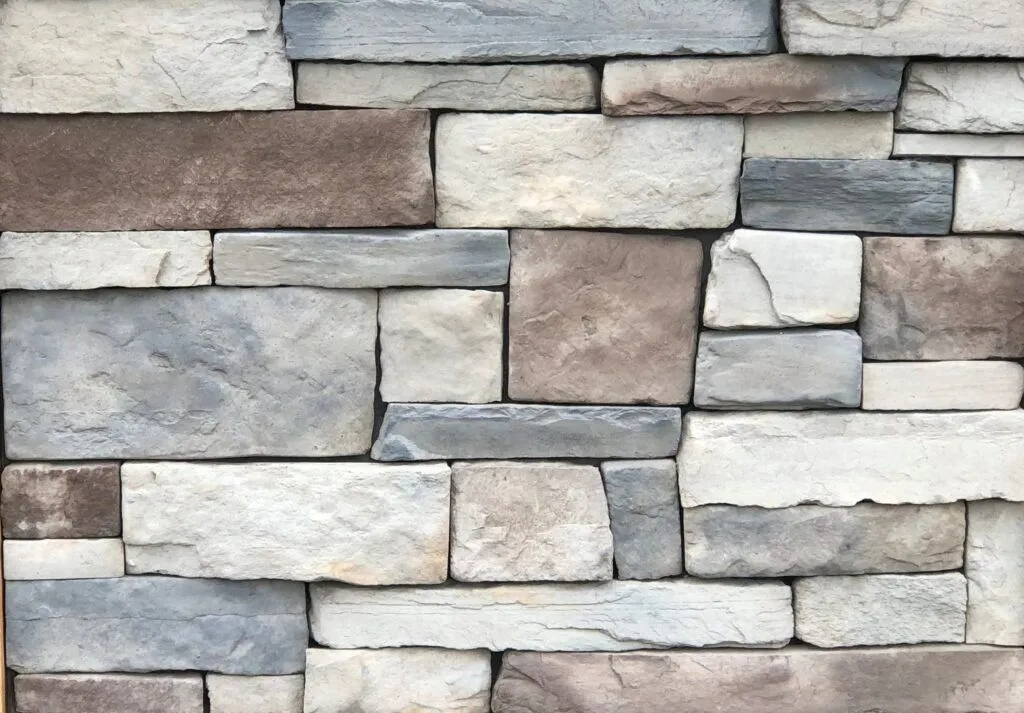Quarry-Blend-Blue-Ridge Patterned stone wall with rectangular, tan, gray, and off-white blocks arranged in a brickwork layout.