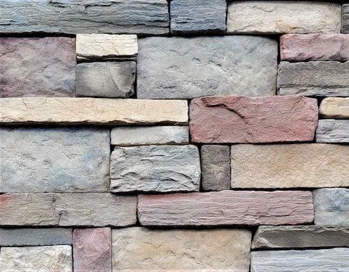 Quarry_Caspian A close-up of a stone wall with rectangular blocks in various shades of gray, tan, and reddish-brown.