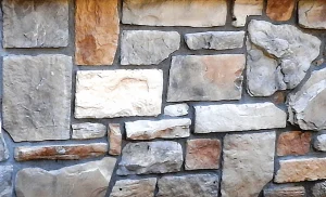 A close-up of a stone wall with variously shaped and colored rectangular and irregular stones.